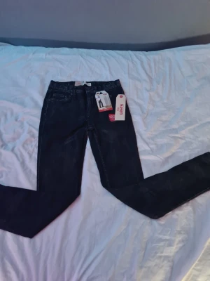 Levi's svarta skinny jeans strl 14y,164 - Säljer ett par svarta skinny jeans från Levi's med klassisk femficksdesign och hög midja. Jeansen har smal passform hela vägen ner och är tillverkade i stretchigt denim för extra komfort. Perfekta för en trendig och avslappnad look.