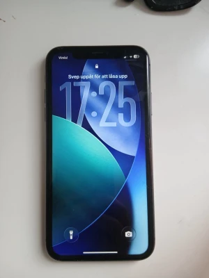 Svart iPhone 11 med dubbla kameror - Säljer en svart iPhone 11 med stilren design och rundade kanter. Telefonen har en baksida i glas, dubbla kameror och Apple-loggan i mitten. Perfekt för dig som gillar snygg och modern teknik. Den har inga sprickor på varken fram eller baksida. Fungerar precis som ny. På övre framsida display har den tre små svarta streck, dock knappt synliga och inget som jag stört mig på. 