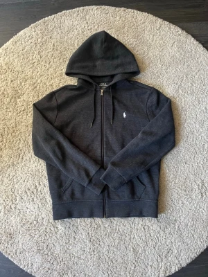 Polo Ralph Lauren Zip Hoodie - Svart/grå zip hoodie från Ralph lauren i storlek M men passar mer Storlek S. Inga problem med den bara att den är för liten för mig. Kanske tvättat den 4 gånger. 