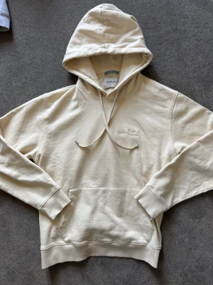 Beige hoodie från Replay - Snygg beige hoodie från Replay med broderad logga på bröstet. Klassisk känguruficka framtill, ribbade muddar och dragsko i huvan. Perfekt för en avslappnad och stilren look. Mjuk bomullskvalitet som känns skön mot huden.
