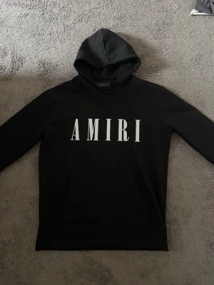 AMIRI Hoodie - Amiri hoodie med detalj på ryggen metallbricka med text. NYSKICK 10/10 helt oanvänd. Storlek Medium passar oxå på Small.