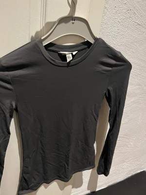 Grå långärmad topp från H&M - En stilren basic grå långärmad topp från H&M med rund halsringning. Nyskick! Strl xs.