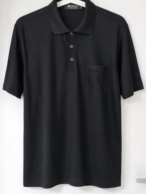 Svart pikétröja från BOSS Hugo Boss i storlek  - Svart pikétröja från BOSS Hugo Boss i storlek M. Klassisk modell med krage, knappar och bröstficka. Mycket fint skick. Snygg både till vardag och mer uppklätt. 