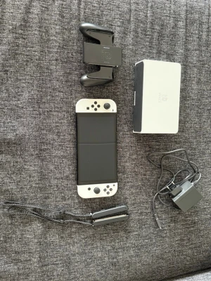 Nintendo Switch OLED vit konsol - Nintendo Switch OLED i vit färg med tillhörande Joy-Con-kontroller, dockningsstation, Joy-Con-grepp och laddare. Köptes Janurair 2026 och har används max 2-3 gånger. Kvitto finns. Pris kan diskuteras vid snabbaffär.