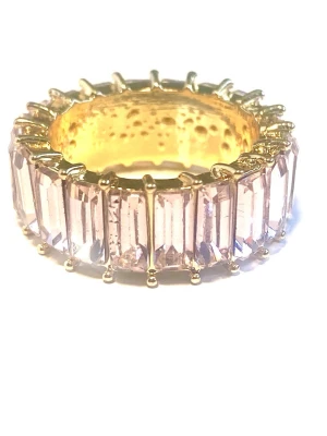 Guldfärgad ring med rosa stenar - Snygg guldfärgad ring med rektangulära ljusrosa stenar runt hela bandet. Ringen har en bred design med stora stenar. Size 7
