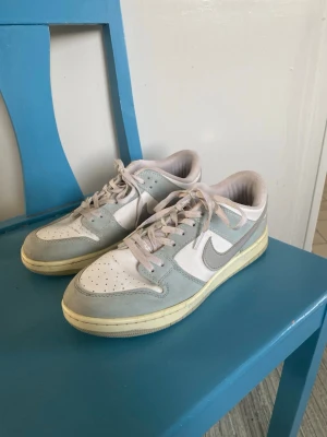 Nike sneakers strl 41 - Snygga Nike sneakers i lågt modell med vit bas och ljusblå/grå detaljer. Skorna är i använt skick och har små defekter, se bild 4. 