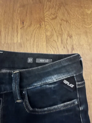 Mörkblå Replay jeans New Luz - Säljer ett par mörkblå jeans från Replay, modell New Luz. Jeansen har smal passform, klassiska fem fickor och kontrastsömmar. Materialet är stretchigt denim som sitter snyggt och bekvämt. Perfekta för dig som gillar en stilren och modern look.
