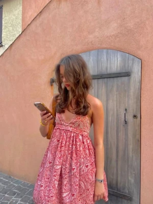 !!INTRESSEKOLL!!Rosa paisleymönstrad kort klänning - Söt kort klänning i rosa med paisleymönster och v-ringad hals. Klänningen har tunna axelband och en luftig passform som ger en avslappnad och somrig känsla. Perfekt för varma dagar och enkel att styla med smycken eller sandaler. Är inte helt säker om jag vill sälja än så de beror på vad jag får för erbjudande.