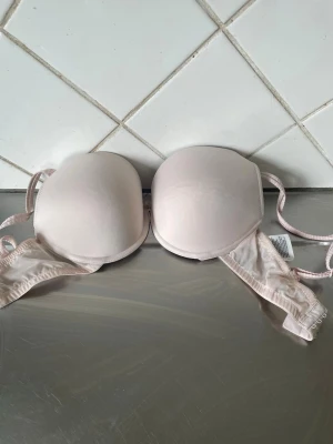 HM Ljusrosa vadderad bh med bygel - H M En enkel och stilren ljusrosa bh med vadderade kupor och bygel för extra stöd. Justerbara axelband och hakknäppning bak. Passar perfekt under ljusa toppar tack vare den diskreta färgen.