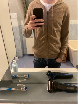 Cashmere hoodie - Säljer en beige hoodie med dragkedja och huva. Hoodien har dragsnören i huvan, två fickor framtill och ribbade muddar vid ärmslut och nederkant. Perfekt för en avslappnad och stilren look. Materialet känns mjukt och bekvämt.  Size L men passar även M från davida!