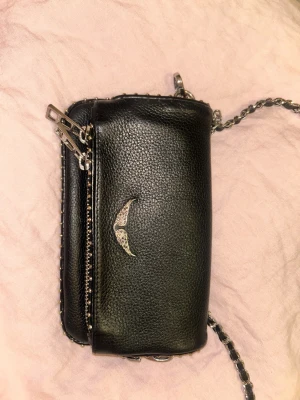 Zadig & Voltaire väska - Svart äkta Zadig Voltaire-väska i gott skick. Utsidan har inga andra tecken på användning, förutom att de silvriga detaljerna har blivit något mörkare. Insidan har vissa bruksspår, men de syns inte utåt! Väskan kan användas som längre axelväska (som på min spegelbild), kortare eller som clutch, eftersom kedjorna går att ta av helt! Nypris ca 340 €.