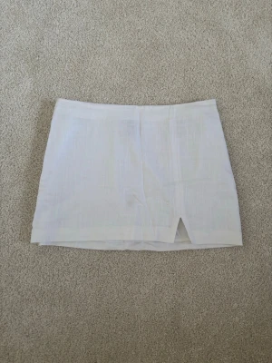 Vit linnekjol  - Snygg vit kortkjol i linne med en liten slits framtill. Kjolen är från H&M och är i storlek 40 men skulle säga att den passar även M. Knappt använd därför i väldigt bra skick.