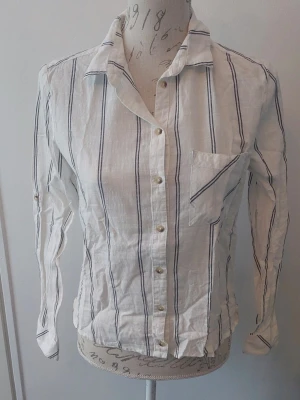 Vit skjorta med svarta ränder. - Vit skön skjorta med svarta tunna ränder. Kort i modellen.