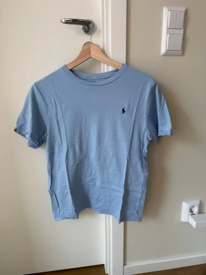 Ljusblå t-shirt Ralph Lauren - Snygg ljusblå t-shirt från Ralph Lauren med klassisk passform. Perfekt basic-plagg till garderoben.
