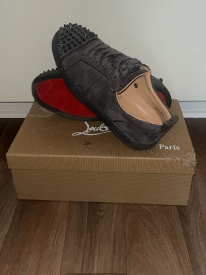 Gråa Louboutin sneakers med nitar - Dags att dessa rakkare ska få en ny ägare. Storlek 42 på dessa. Skorna har inget tecken på nån slags skada eller användning. Skriv via intresse så kan pris diskuteras. Äkthet= garanterad då kvitto på skorna finns