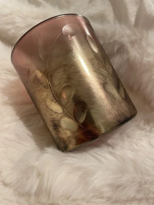 Rosa och guld glaslykta med bladmotiv - Säljer en dekorativ glaslykta i rosa och guld med ingraverat bladmotiv. Lyktan har en rund form och är perfekt som ljushållare eller dekoration. Materialet är glas och färgskiftningen ger ett lyxigt intryck. Passar snyggt i alla rum för extra mysfaktor.