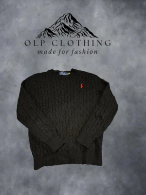 Svart kabelstickad tröja Polo Ralph Lauren - Kabelstickad svart tröja från Polo Ralph Lauren med rund halsringning och den klassiska röda logotypen broderad på bröstet. Tröjan har långa ärmar och ribbade muddar vid ärmslut och nederkant. Perfekt för en stilren och avslappnad look. Modellen på bilden är 184cm lång och bär storleken M. #11