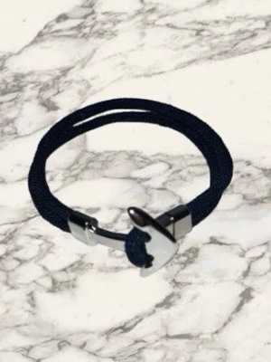 Marint armband med ankardetalj - Snyggt armband med marinblått rep och en silverfärgad ankare som lås. Armbandet har en stilren och modern design, perfekt för dig som gillar nautiska detaljer. Tillverkat i textil och metall för en cool kontrast.