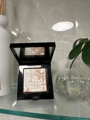 Bobbi Brown Shimmer Brick Highlighter -  Bobbi Brown Shimmer Brick Highlighter i en fyrkantig svart dosa med spegel. Highlightern har flera skimrande nyanser i champagne, rosa och guld som ger ett glowigt resultat. Perfekt för att framhäva kindben och ge lyster till ansiktet. Endast testad 