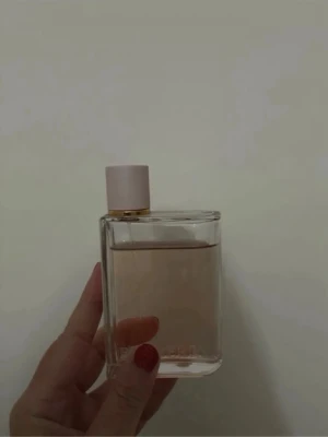 Burberry parfym 100 ml  - Stilren parfymflaska i genomskinligt glas med ljusrosa lock och gulddetalj. Flaskan har en rektangulär form och innehåller en ljusrosa vätska. Perfekt för dig som gillar minimalistisk design och eleganta dofter.