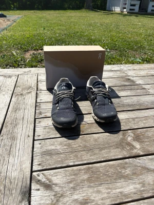 Marin blå On cloud sneakers - Snygga marinblå sneakers från On cloud med vita detaljer och grå snören. Skorna har en låg profil och är tillverkade i mesh och syntetmaterial för bra andningsförmåga och komfort. Perfekta för dig som gillar sportig och stilren design. Bara att skriva vid frågor eller funderingar!