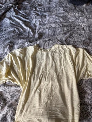 Ljusgul långärmad topp - En enkel och stilren ljusgul långärmad topp med rund halsringning. Toppen har en rak passform och är tillverkad i ett mjukt material som känns skönt mot huden. Perfekt att matcha med jeans eller kjol för en avslappnad look.