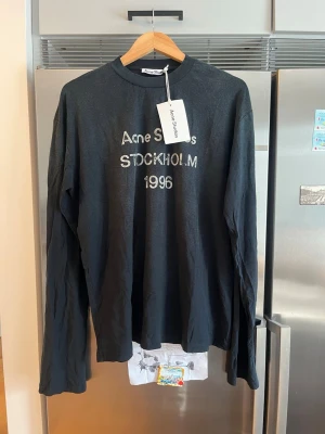 Svart långärmad topp Acne Studios - Här är en kort och säljande text:  Acne Studios Stockholm 1996 Long Sleeve  Helt ny med tags kvar. Stilren svart long sleeve med ikoniskt Stockholm 1996-tryck. Tillverkad i Portugal och i mycket hög kvalitet.  Storlek: M Skick: Nytt Pris: 1050 kr  Öppen för seriösa bud.