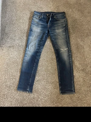 Levis 511  - Säljer ett par blå jeans med slitningar. Jeansen har klassisk femficksmodell, normal midja och smal passform. Snygg tvätt med ljusa partier. Perfekta för en avslappnad och trendig look. 