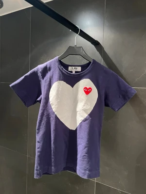 CDG t-shirt - Hej, säljer nu denna t-shirten från Comme Des Carçons i storleken S. Den är i färgen marinblå och har ett vitt hjärta på framsidan. Skick 8/10 mycket fint skick. Längd: 57cm Axel - axel: 36cm Armhåla - armhåla 39cm Skriv om du har några frågor eller funderingar!