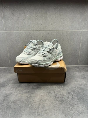 Gråa asics Gel - Snygga ljusgrå sneakers från Asics med mesh- och syntetpaneler för en sportig vibe. Skorna har en chunky sula och klassisk snörning. Perfekta för dig som gillar stilrena och bekväma sneakers med modern design.