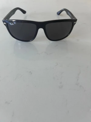 Ray-ban boyfriend - Klassiska svarta Wayfarer solglasögon från Ray-Ban med bred båge och mörka glas. Snygg och tidlös design med Ray-Ban-logga på sidan. Perfekta för dig som vill ha en ikonisk look och skydda ögonen mot solen.