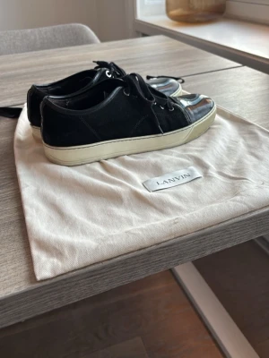 Lanvin Sneakers Äkta – Billigt Pris 🔥 - Lanvin Sneakers – Äkta 🖤  Säljer mina äkta Lanvin sneakers i svart läder med lackad tå. Kommer med original Lanvin-påse/dustbag.  Skorna är använda och har normalt slitage, men är fortfarande riktigt snygga och har mycket kvar att ge. Se bilder för skick.  Pris: 1450 kr – säljer dem billigt eftersom jag behöver få in lite pengar snabbt, så först till kvarn gäller.  ✅ 100% äkta ✅ Originalpåse medföljer ✅ Klassisk Lanvin-modell  Storlek: [43]  Skicka meddelande vid intresse mvh Eric