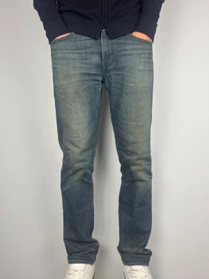 Blå Levi's raka jeans - Levis 511 med riktigt snygga fades i en unik och snygg färg. Dessa är väldigt unika! Skick: B Grade, lagade i grenen av professionell skräddare som inte påverkar vid användning.  Färg: Distressed blå färg med mycket fades  | Modell: 511 | Storlek: W32 L32 | Passar på modellen som är 189 cm och 82 kg. Något lite små i längden bara på honom.   Mått: (Måttavvikelse +-1cm) A: 43 cm B: 104 cm C: 19 cm D: 26 cm  Tveka inte att höra av dig minsta fråga eller fundering!  Skickas snabbt!