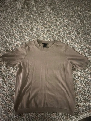 Beige kortärmad finstickad topp - Snygg beige topp från Lindex med korta ärmar och rund halsringning. Användt sparsamt bara några gånger så inga direkta defekter(hund finns i hemmet) 