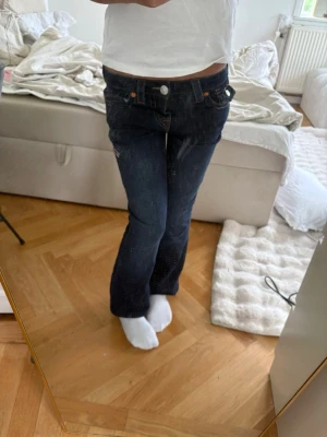 Mörkblå bootcut jeans från true religon  - Snygga mörkblå bootcut jeans med låg midja och klassiska fem fickor. Jeansen har orangea sömmar och silverfärgade knappar. Perfekta för en avslappnad och trendig look. Materialet är denim i bomull. De är avklippta så de är lite förkorta för mig som är 153m❗️KAM SÄNKA PRISET❗️ använda 1-2 gånger w23💕💕
