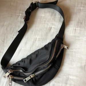Svart Midjeväska  - Denna svarta midjeväska med mycket blixtlås detaljer är köpt från TopShop för något år sedan! Bortsätt från några resningar och missfärgningar på något av blixtlåsen så är den i jättebra skick! Den är otroligt praktisk och rymmer mycket samt har många olika fack😊