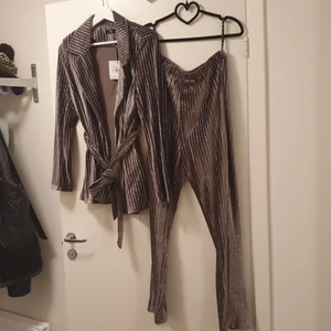 Missguided kostymset  - Nytt kostymset från missguided. Lappar fortfarande kvar! Setet är grått i velour med silvriga glittriga ränder. Överdel storlek 42 och underdel storlek 40.
