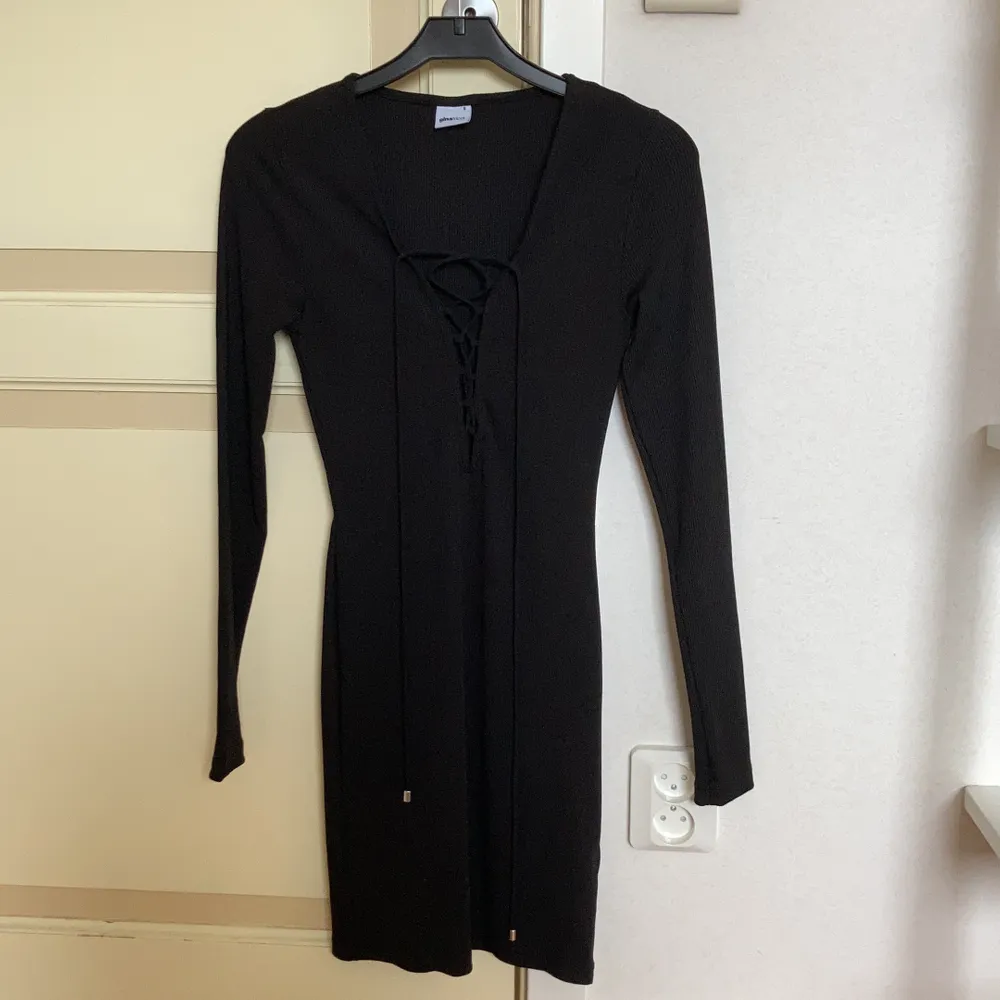En svart, ribbad klänning från Gina Tricot i strl S. Låg urringning med snörning, tight passform.. Klänningar.