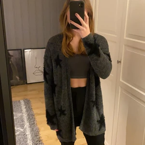 Kofta med stjärnor - En längre grå kofta med svarta stjärnor. Bra skikt och knappast använd. Strl S och märket Miss snob. OBS! Köparen står för frakten.