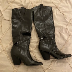 Cowboy boots  - Snygga knähöga boots i cowboy/western stil. Svarta i lack-liknande finish och ormmönster. Blir tyvärr inte använda i särskilt stor utsträckning! Väldigt fint skick. 