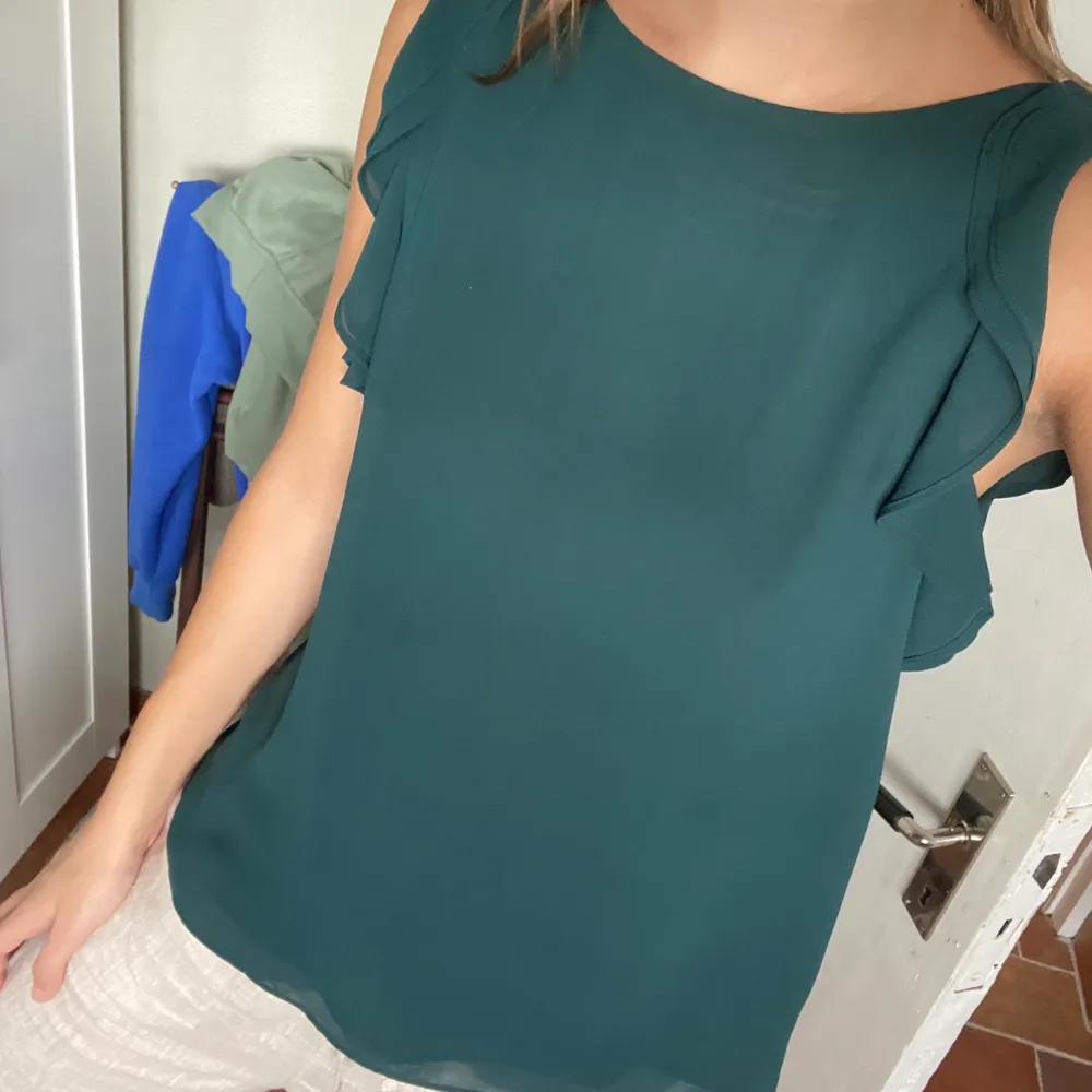 Grön kortärmad blus från H&M! Den har fina detaljer vid ärmarna. Baktill finns en knapp som man knäpper. Den är i storlek 34 men passar även 36, vilket jag är. Köparen står för frakten🥰. Blusar.