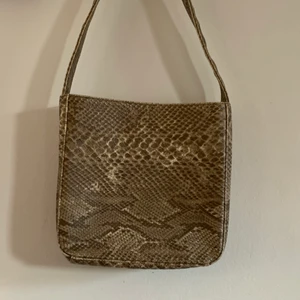 Ormskinns handväska - Cool handväska med ormskinnslikanande material! Innerficka innuti. Mått: 22x23x7 cm. Axelbandet: 55x3,5 cm