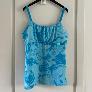 Y2K topp  - Sött linne i turkosblått, väldigt y2k stil 💙🌸 Vadderad där fram kring bysten, och väldigt lätt-silkigt tyg! Storlek L/42 o passar fint upp till 44 också - jag har E-kupa o den passar mig bra 💜🥰 Köpt secondhand, den är från Kappahl tidigt 00-tal. Jättefint skick, inga skavanker alls 💕 Säljes då den inte kommer till användning 😭