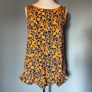 A-linjeformad blus - Gulligaste 60-tals a-linjeformade blusen! Supersnyggt mönster och man kan ha den åt båda hållen. Två fickor på ena sidan, pärlemorsknappar på andra sidan och söt liten volangkant. Använd vid ett tillfälle för en fotografering. Spana gärna in mina andra annonser för samfrakt!