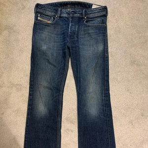 Lågmidjade jeans från diesel  - Säljer mina assnygga lågmidjade jeans från diesel. Storlek är W32, L32. Jeansen är i en snygg mörk blå färg, och utsvängda i modellen. Jeansen har även en snygg detalj på bakfickorna av jeansen (se bild 2). Älskar dessa jeans men de är lite för stora så kommer inte till användning. Det är ingen defekt på jeansen, de är i nyskick. Skriv för mer bilder.           Kan mötas upp i Göteborg, annars står köpare för frakt. 