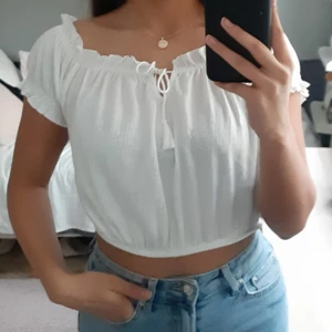 Cropped topp - En vit croptop med knyt detalj i fram. Aldrig andvänd. Funkar både som off-shoulder eller on-shoulder. Köpt som storlek L men passar som en S/M. Kan mötas upp i Uppsala eller posta men köpare står för fraktkostnader. 