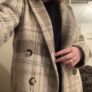 Rutig kappa - Säljer denna superfina kappan från H&M! köpt för 2 år sen men har aldrig riktigt fått användning för den. perfekt som höst/vårjacka. Frakt tillkommer! :)