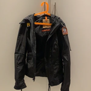 Svart PARAJUMPERS regnjacka - Väldig snygg regnjacka. Köpte den för 2 år sedan och den ser fortfarande helt ny ut. Det är en riktig Parajumpers märke som man kan se på andra bilden. Har ingen användning av den längre💕 Nypris: 4500 kr