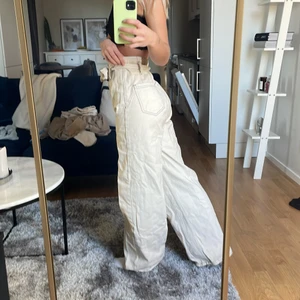 vita/beiga jeans med knytning  - vita/beiga jeans från nelly med knytning. skrynkliga på bilden för de legat länge i garderoben. supersnygga med hög midja i storlek W26 han mötas upp i sthlm elr fraktas som köparen står för