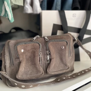 Núnoo Ellie new suede  - Núnoo väska i mycket bra skick. Kommer tyvärr inte till användning längre, inte längre min stil. Stilren grå/beige färg, perfekt nu till våren! Finns även ett axelremsband till. Inköpt för ca 1500kr. Säljer för 500kr+frakt eller högsta bud!🪐